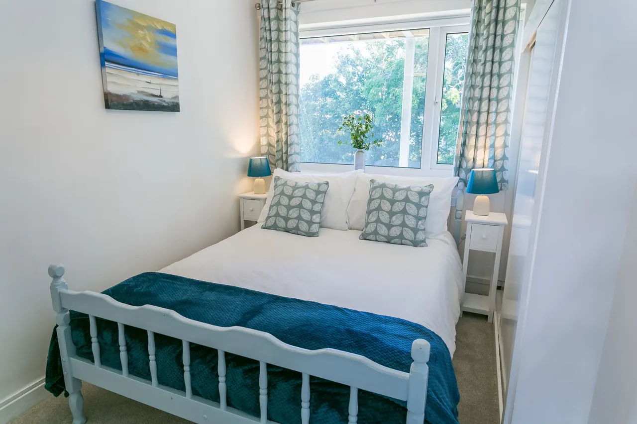 Double bedroom with teal bed frame and soft coastal styling